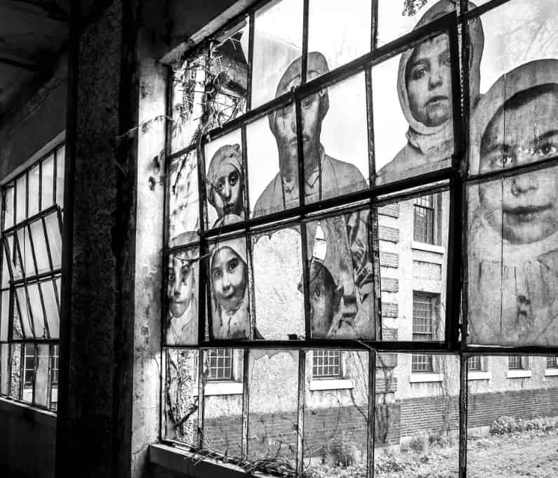 Cristalera del hospital abandonado de la Isla de Ellis con los rostros de inmigrantes tratados.